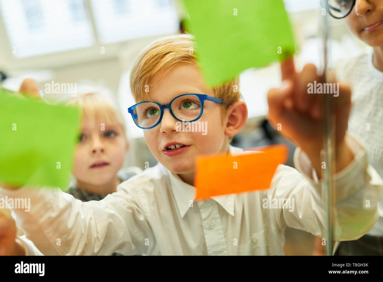 Boy als Geschäftsmann Analysen Ideen auf, rutscht während kreatives Brainstorming Stockfoto