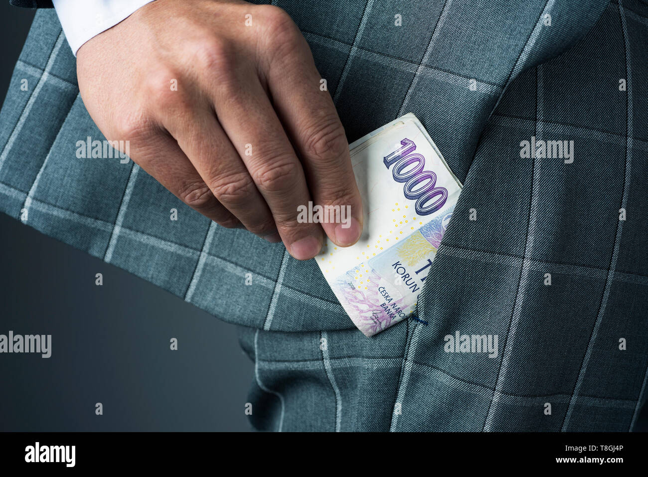 Nahaufnahme eines jungen Geschäftsmann, tragen einen eleganten grauen Anzug, oder einige Tschechische Kronen Banknoten in die Tasche seiner Hose Stockfoto