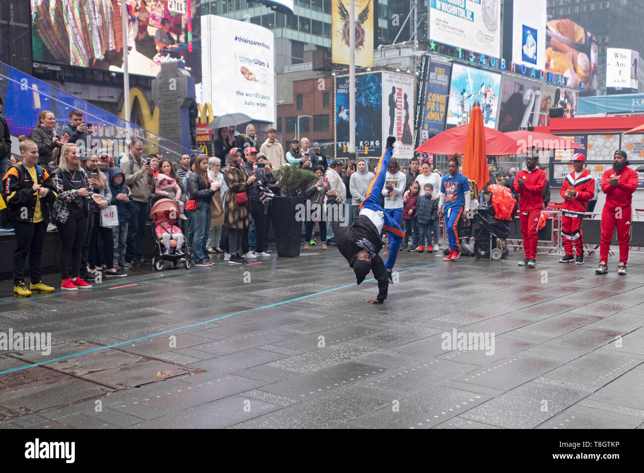 Acrobat Gymnastik Gaukler durchführen für eine Masse von Touristen an einem regnerischen Wochenende Morgen. Times Square, Manhattan, New York City. Stockfoto