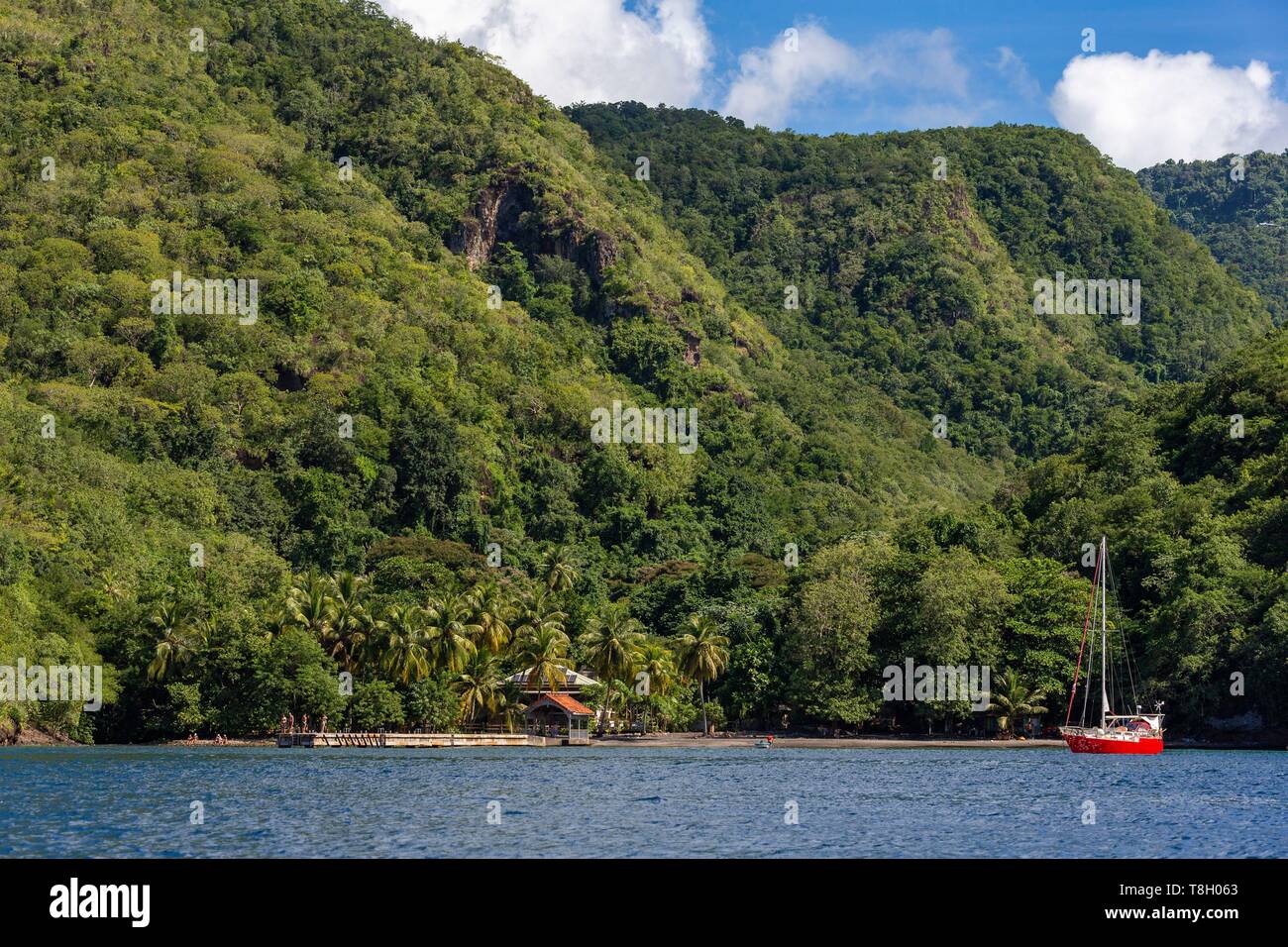 Martinique, Karibik, schwarz Cove mit dem Ponton und schwarzem Sand Strand, vor Anker eine rote Segelboot Stockfoto