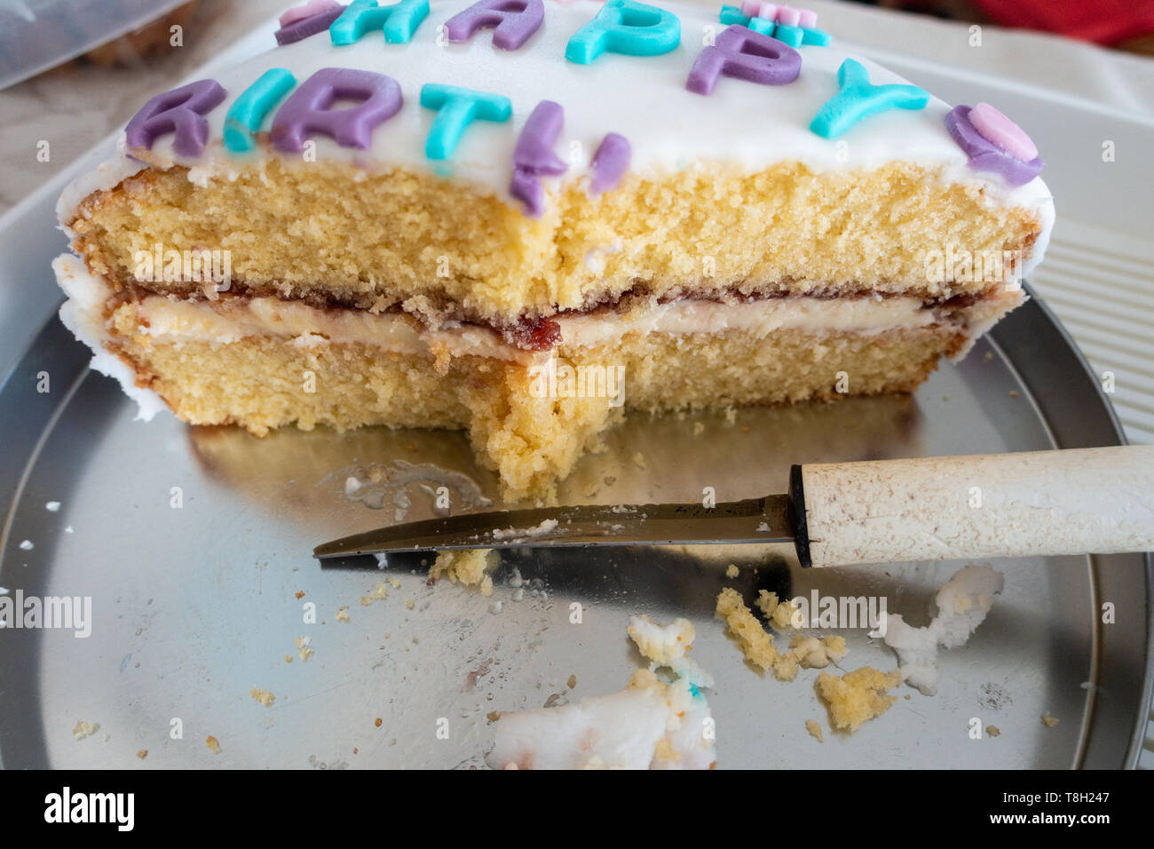 Eine halbe Torte auf einem Tisch mit einem Messer gegessen. Stockfoto