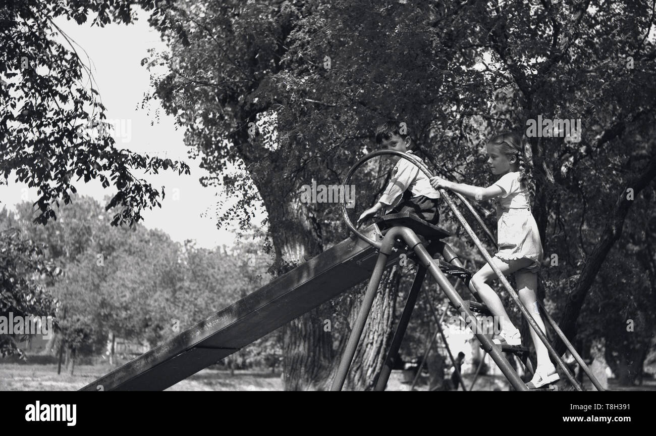 1970 s, historischen, zwei junge Kinder außerhalb playig auf einem Metall folie neben einem Waldgebiet, USA. Stockfoto