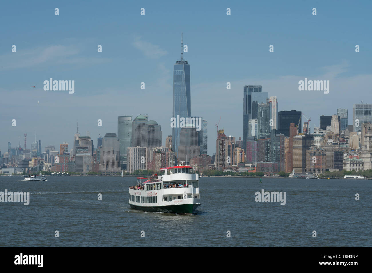 Die Skyline von Lower Manhattan mit einem Circle Line Sightseeing boot Touristen, die rund um den Hafen von New York. Mai 8, 2019 Stockfoto
