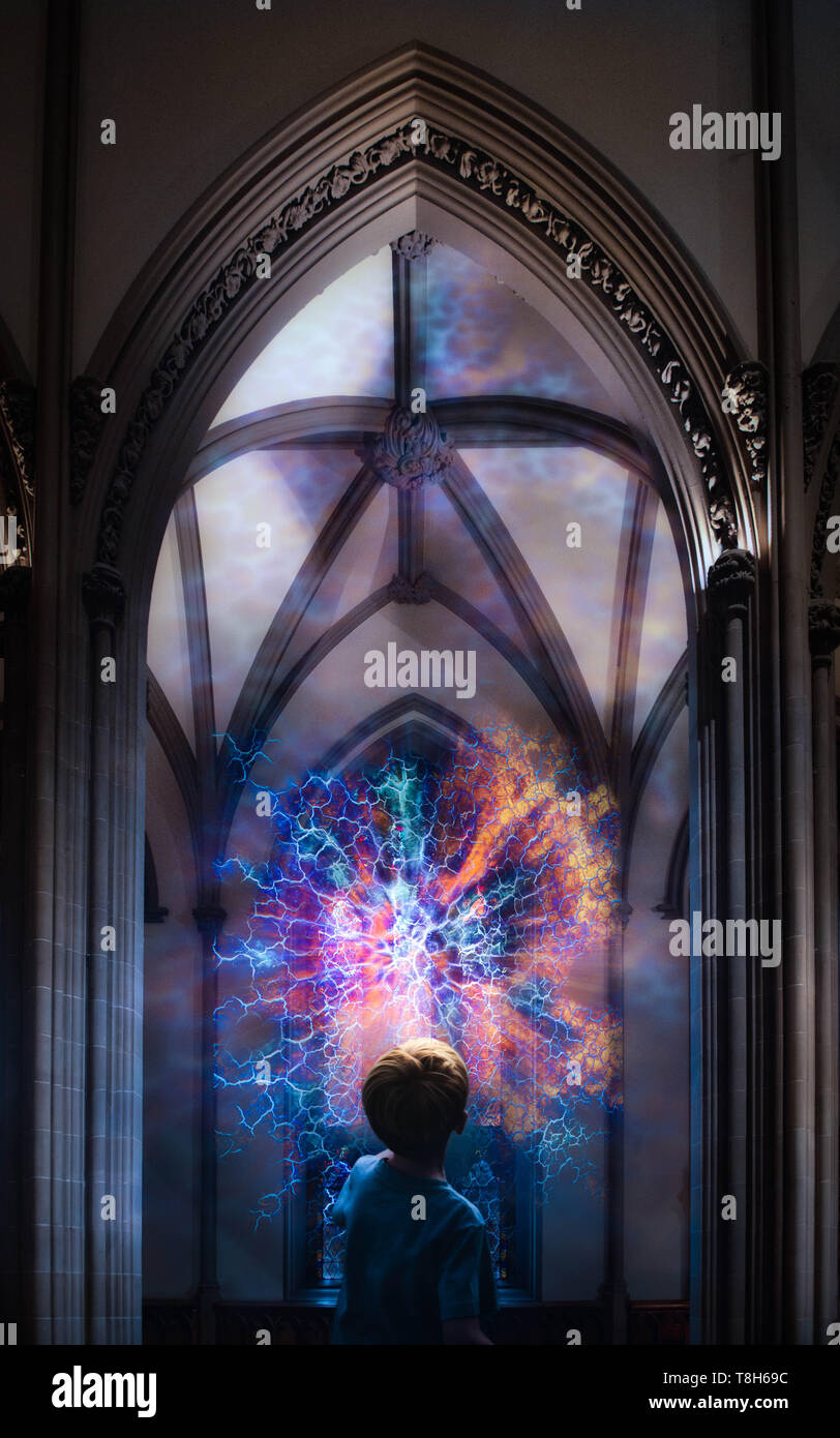 Junge schaut auf einen Lichtblitz aus einem Glasfenster in der Kathedrale Stockfoto