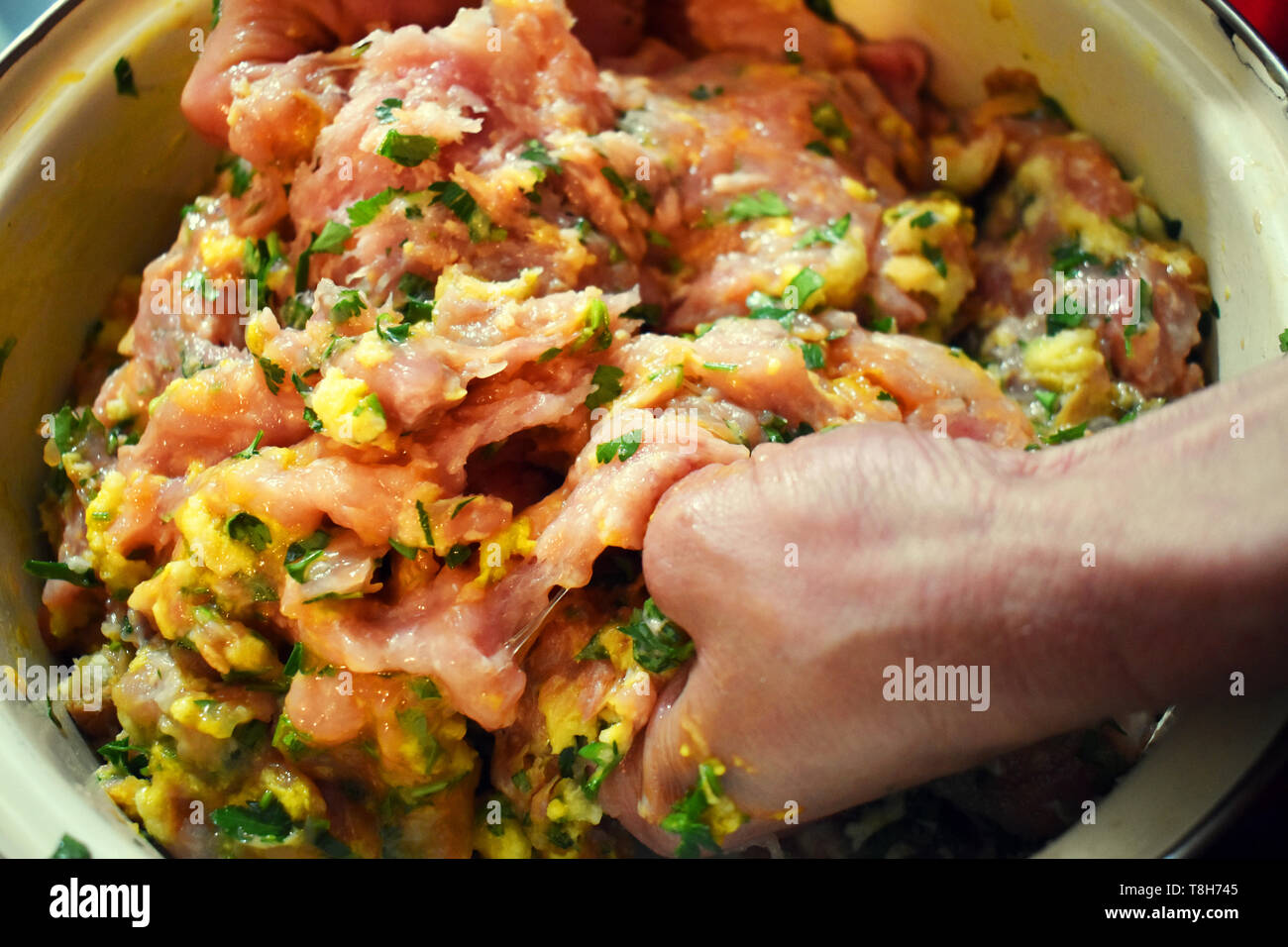 Frau Hände bereiten miced frisches Fleisch für die fleischbällchen. Manuell mischen das Fleisch mit Eiern, Petersilie und Knoblauch. Stockfoto