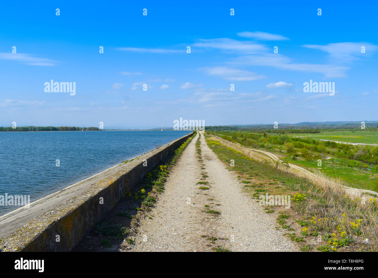 Land straße entlang des Lake Dam an einem sonnigen Sommertag mit perfekter blauer Himmel Stockfoto