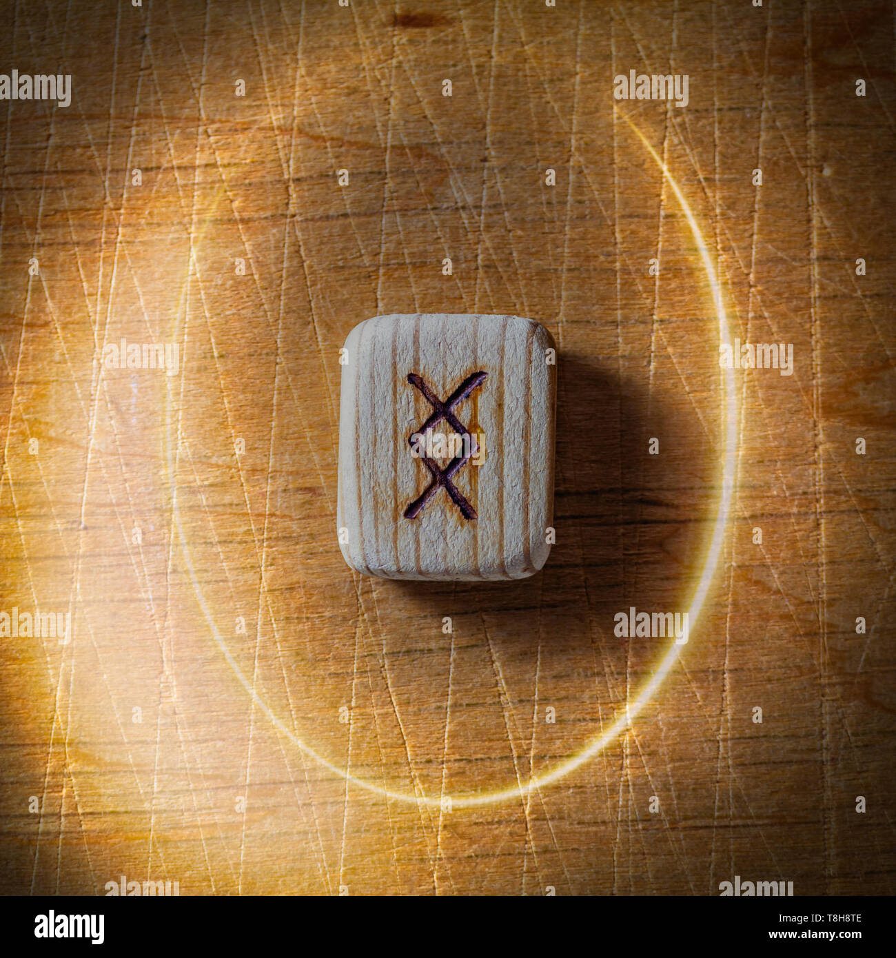 Ingwaz. Handgefertigte skandinavischer Runen aus Holz auf Holz vintage Hintergrund in einem Kreis aus Licht. Konzept der Wahrsagerei und Vorhersage des Stockfoto