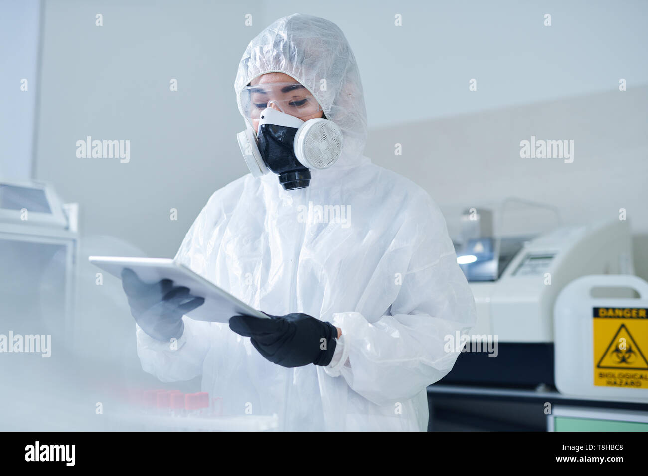 Biologe im schützenden Kostüm mit Tablet Stockfoto