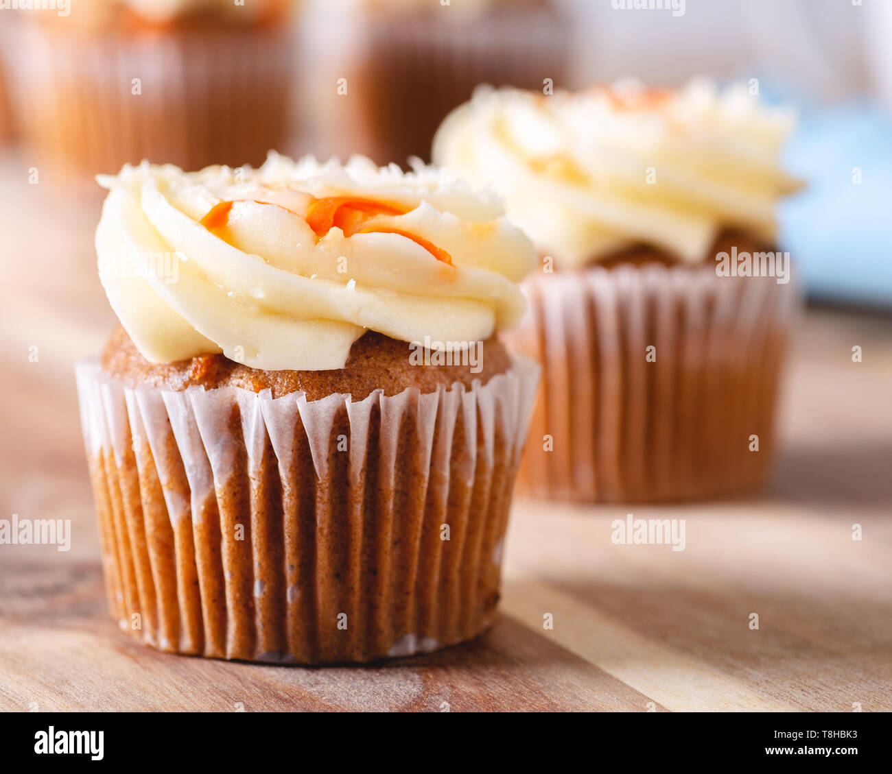 Nahaufnahme einer Karotte Cupcake mit Frischkäse Puderzucker und Cupcakes im Hintergrund Stockfoto