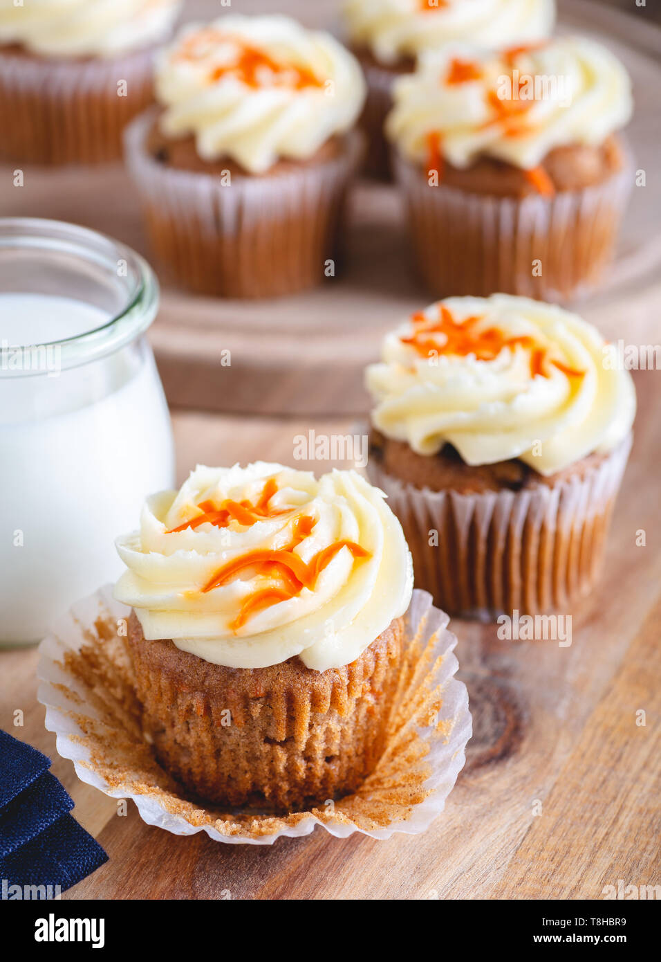 Karotte Cupcake mit Frischkäse Vereisung und Glas Milch und Cupcakes im Hintergrund Stockfoto