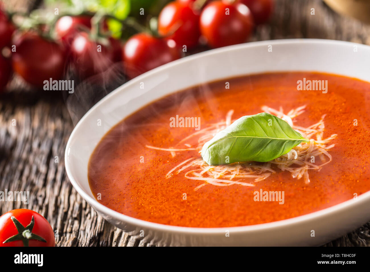Hot Tomato Soup Parmesan und Basilikum verlassen auf alten oal Tabelle Stockfoto