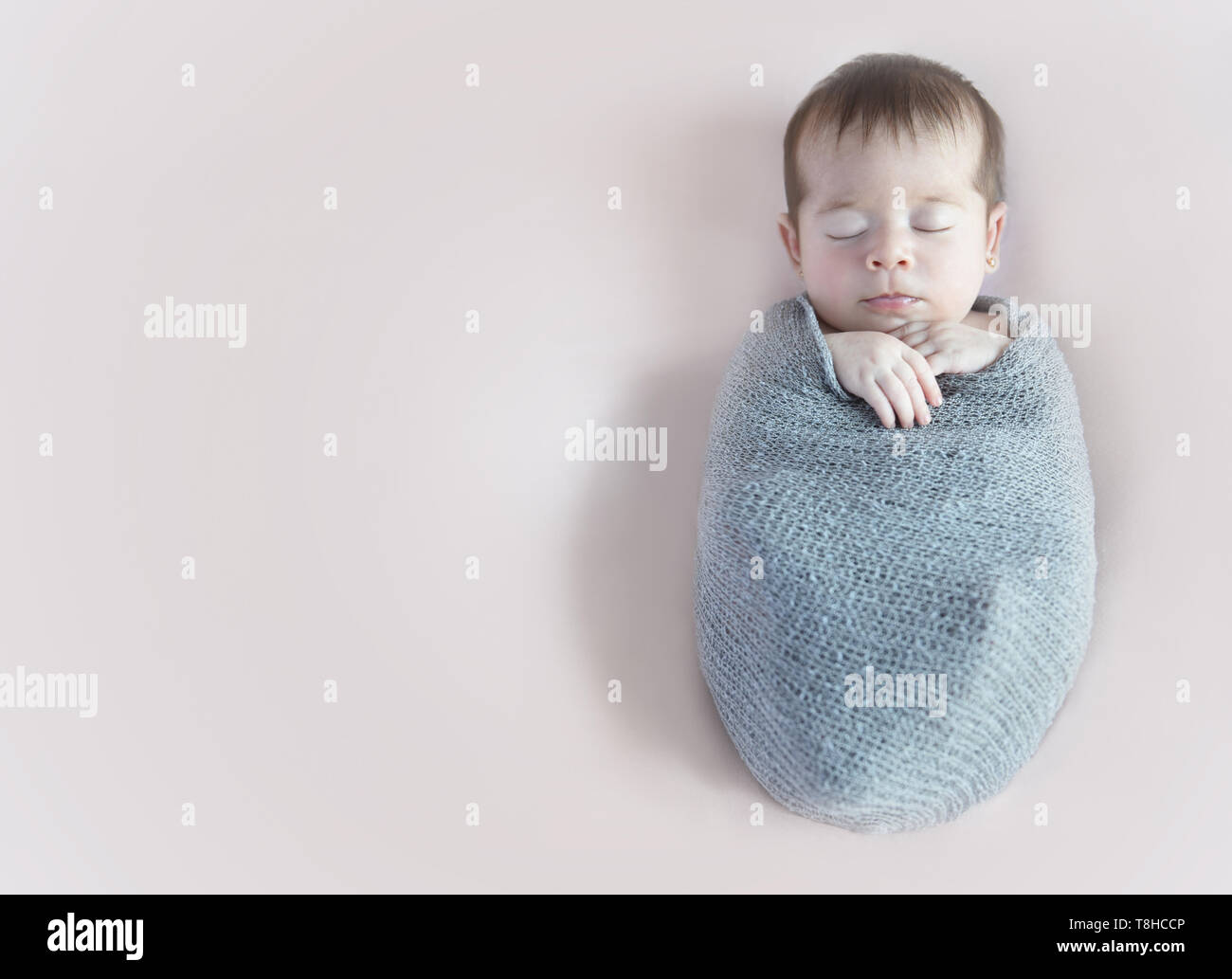Neugeborenes Mädchen slepping Umhüllung in eine graue Decke Stockfoto