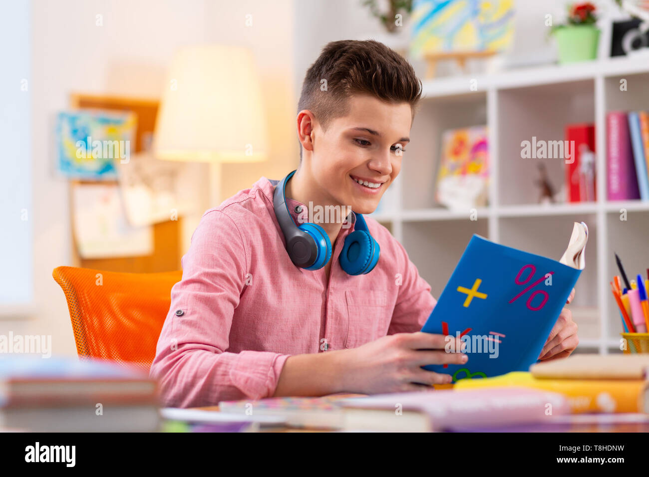 Student trägt Kopfhörer an seinem Hals lesen Mathe Buch Stockfoto