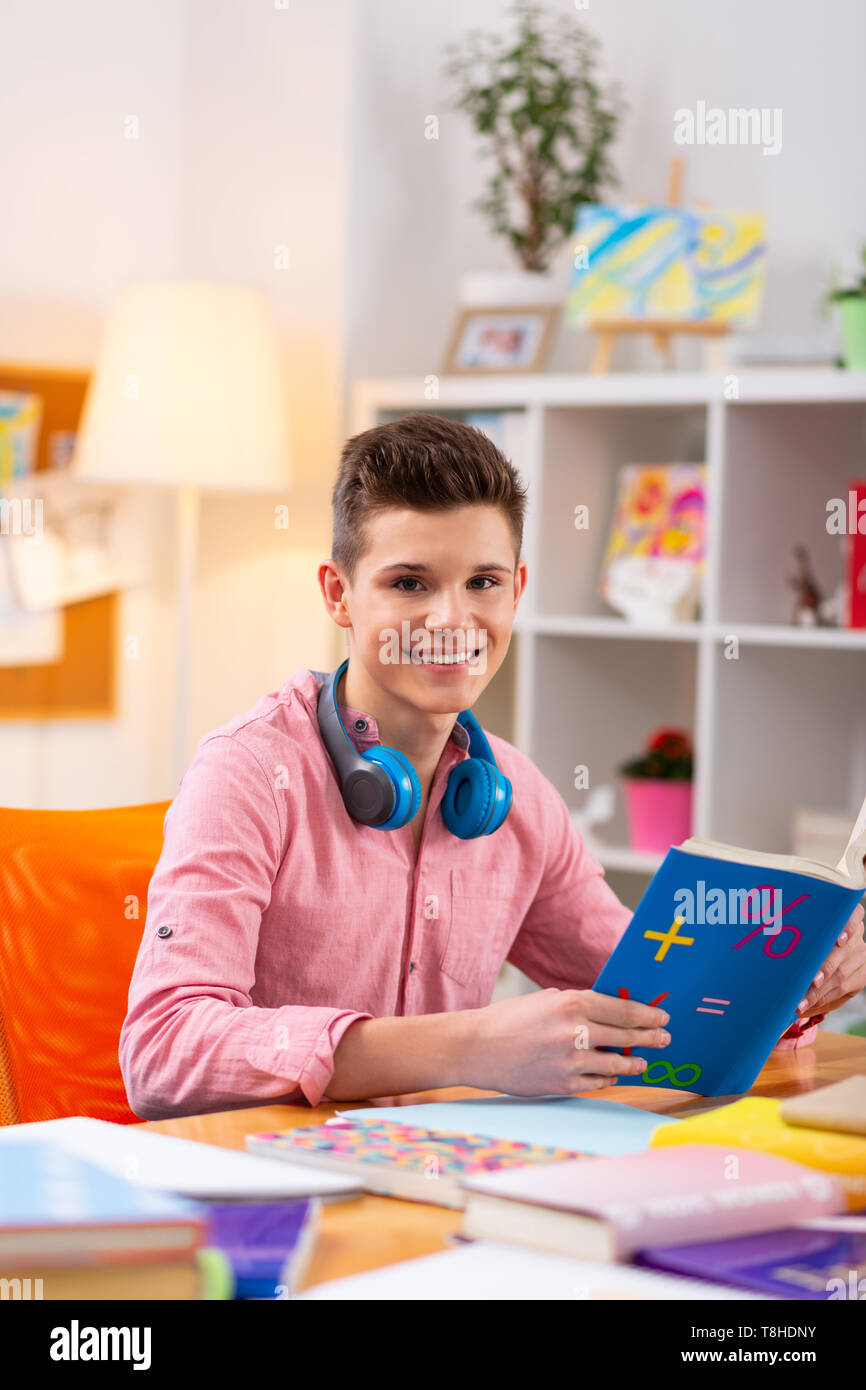 Fröhlicher student Mathematik lesen Buch beim Sitzen am Tisch Stockfoto