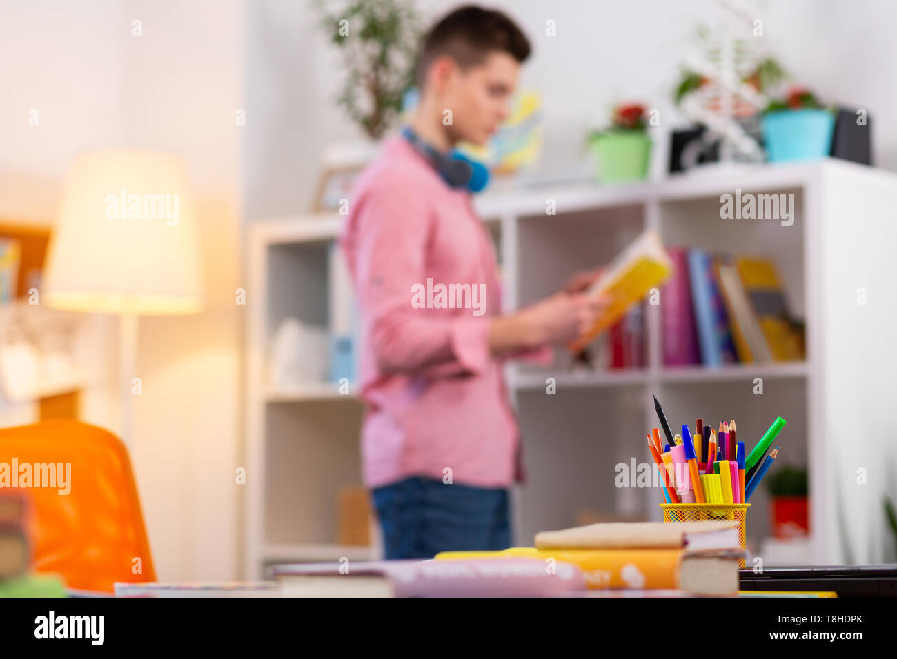 Tabelle mit Briefpapier und Bücher in der Nähe von Student lesen Buch Stockfoto