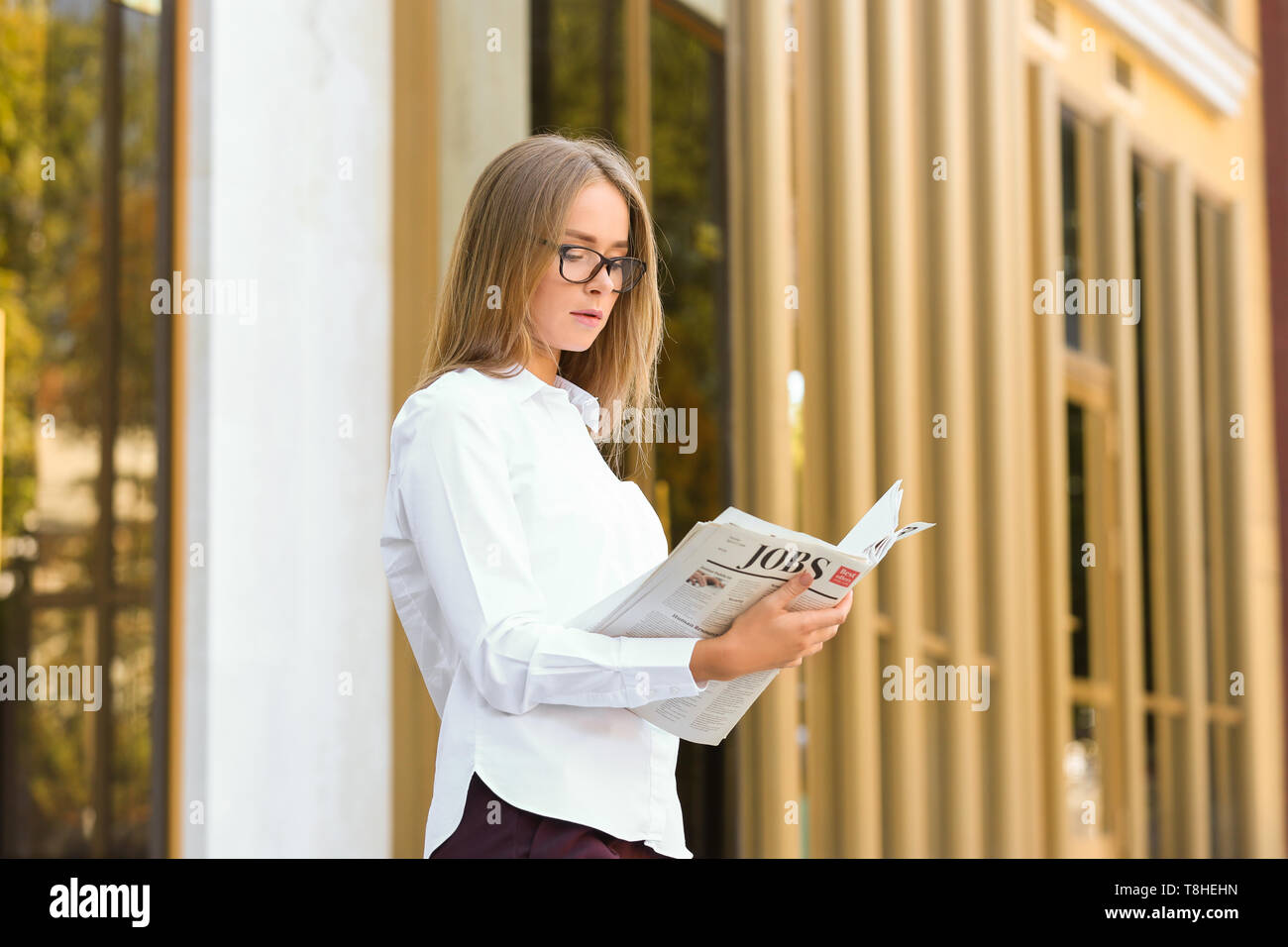 Junge Geschäftsfrau lesen Zeitung im Freien Stockfoto
