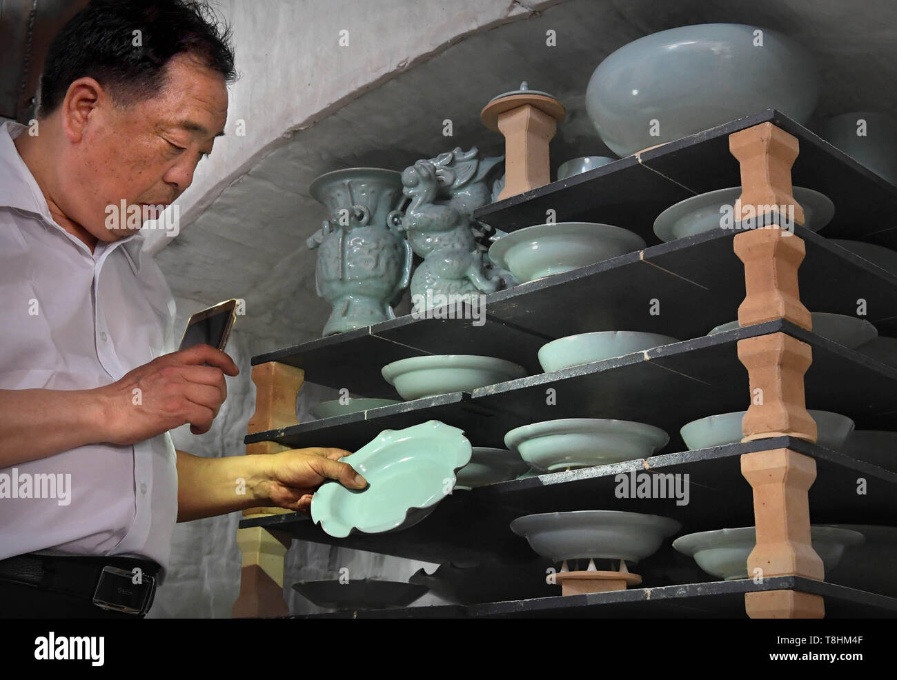 (190513) - Peking, 13. Mai 2019 (Xinhua) - Wang Junzi Kontrollen Ru Porzellan nur gefeuert in seinem Studio in Qingliangsi Dorf, baofeng Grafschaft von der Central China Provinz Henan, 9. Mai 2019. Ru Porzellan, einer der fünf bekannten Arten von Porzellan während der Song Dynastie (960-1279) im alten China, ist für seine azurblaue Farbe bekannt, leichten Körper, zarte Korn und sanften Textilien. Wang Junzi, geboren 1960, ist ein Ru Porzellan feuern Handwerker in Qingliangsi Dorf Baofeng Grafschaft in der zentralen China Henan, wo die alten offiziellen Ru Porzellan Ofen in der Song Dynastie befindet. Um zu reproduzieren. Stockfoto