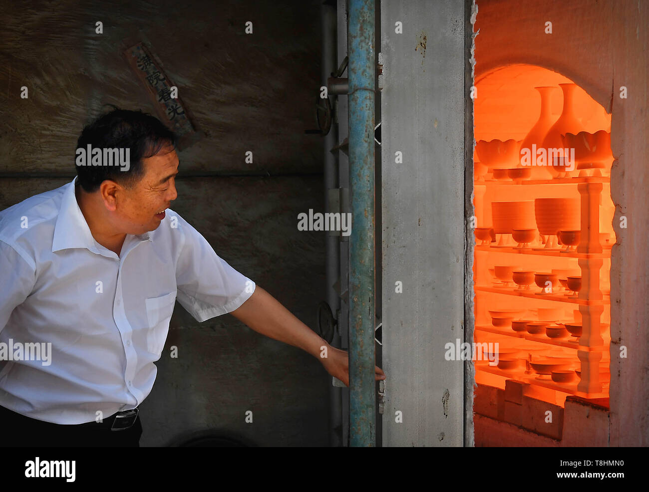 (190513) - Peking, 13. Mai 2019 (Xinhua) - Wang Junzi öffnet Ru Porzellan Ofen in seinem Studio in Qingliangsi Dorf, baofeng Grafschaft von der Central China Provinz Henan, 9. Mai 2019. Ru Porzellan, einer der fünf bekannten Arten von Porzellan während der Song Dynastie (960-1279) im alten China, ist für seine azurblaue Farbe bekannt, leichten Körper, zarte Korn und sanften Textilien. Wang Junzi, geboren 1960, ist ein Ru Porzellan feuern Handwerker in Qingliangsi Dorf Baofeng Grafschaft in der zentralen China Henan, wo die alten offiziellen Ru Porzellan Ofen in der Song Dynastie befindet. Um die Beau reproduzieren Stockfoto