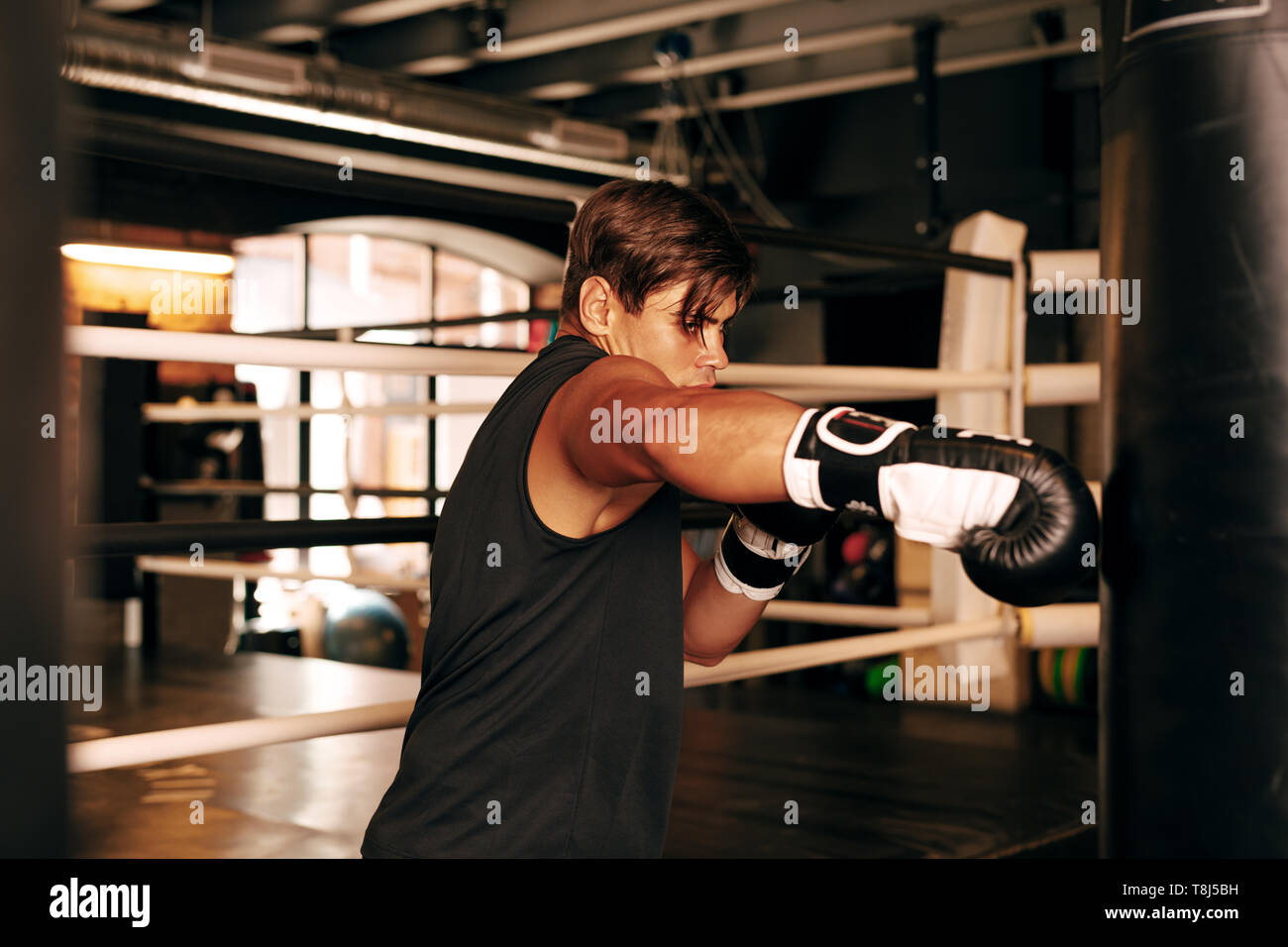 Muskulöse Athleten trainieren Sie im Fitnessraum auf einen Boxsack aus Leder Stockfoto