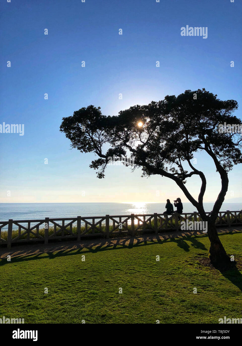 Paar sitzt auf einem Zaun Fotos und ein Blick auf die Ansicht, Santa Monica, California, United States Stockfoto