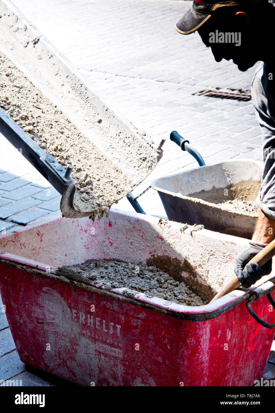 Hart arbeitend Mann schaufelt Fundament gemischten Beton aus großen Container, die in einem Rutsche geliefert wird, Stockfoto