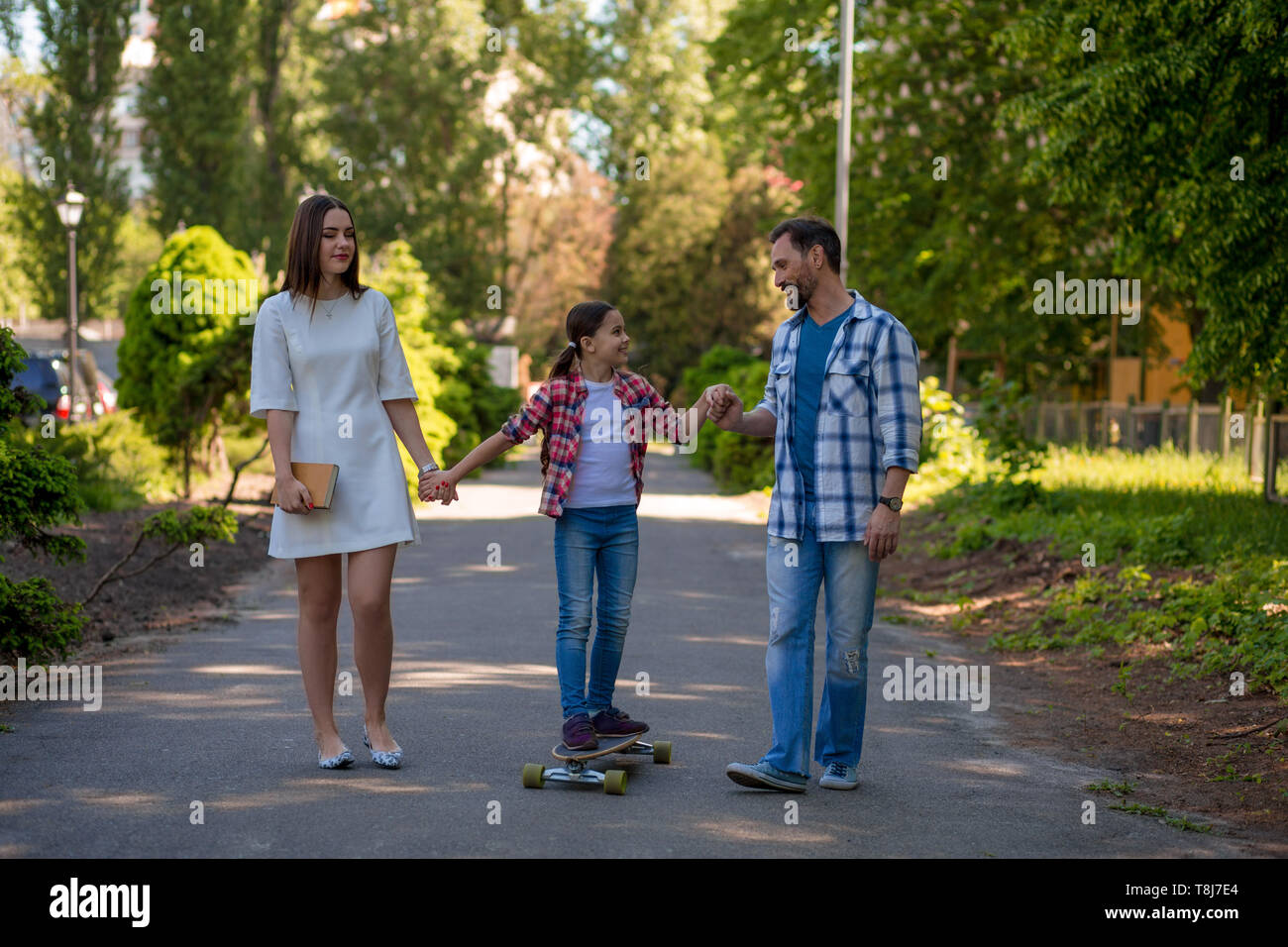 Lächelnd Familie mit einem Skateboard im Sommer Park Stockfoto