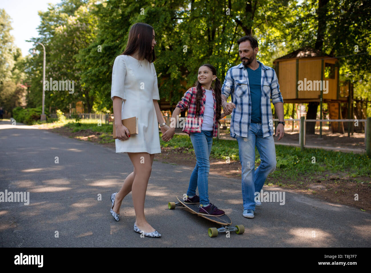 Lächelnd Familie mit einem Skateboard im Sommer Park Stockfoto
