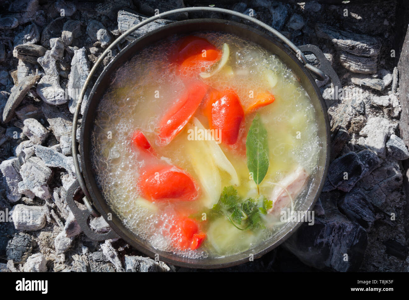 Shurpa Suppe mit Gemüse in großen gusseisernen Kessel outdoor. Sommer essen für Wanderung. Ansicht von oben. Türkische Küche. Stockfoto