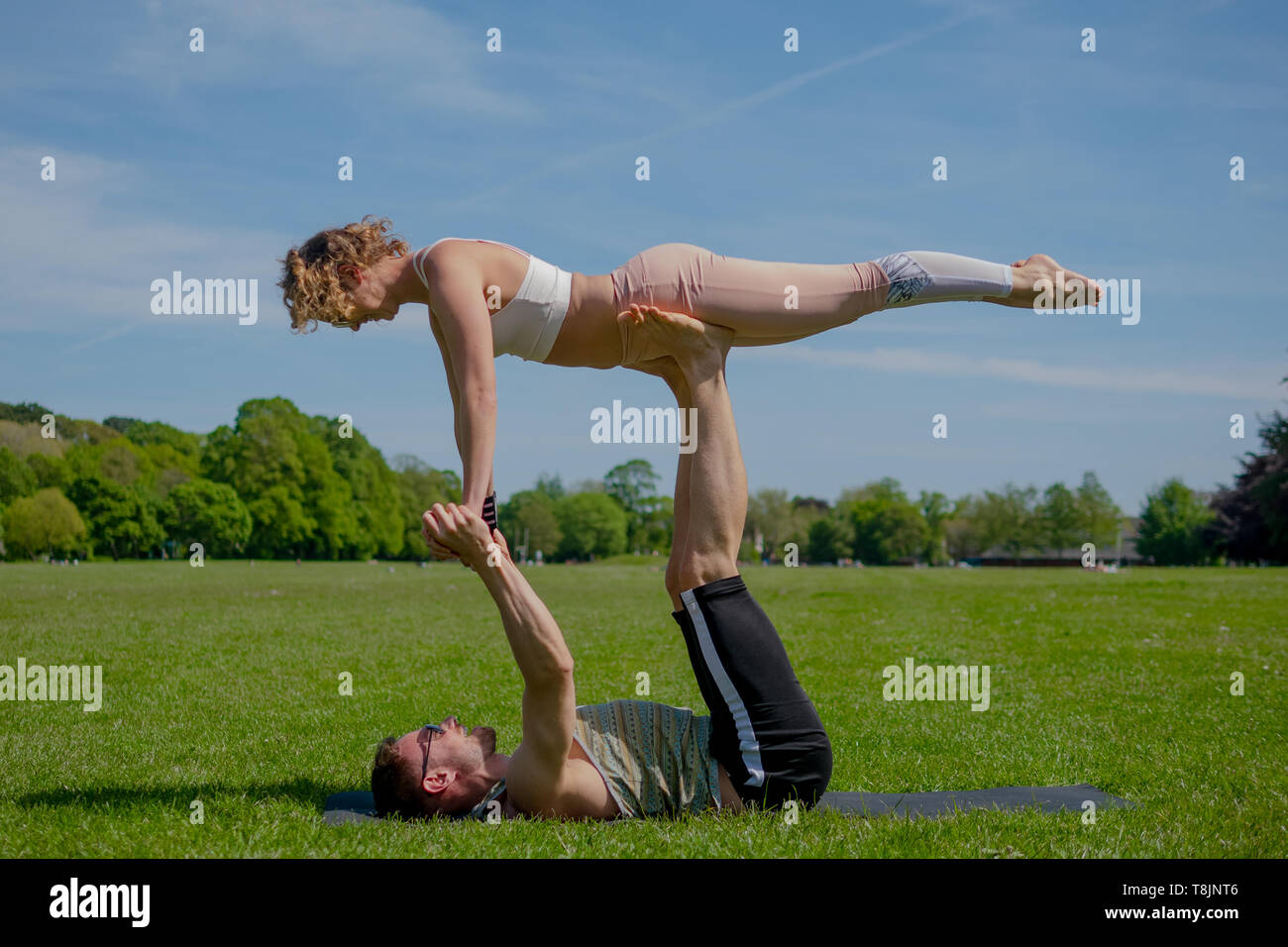 Junge athletische verliebtes Paar Durchführung acro Yoga im Roath Park auf einem hellen, sonnigen Tag. Stockfoto