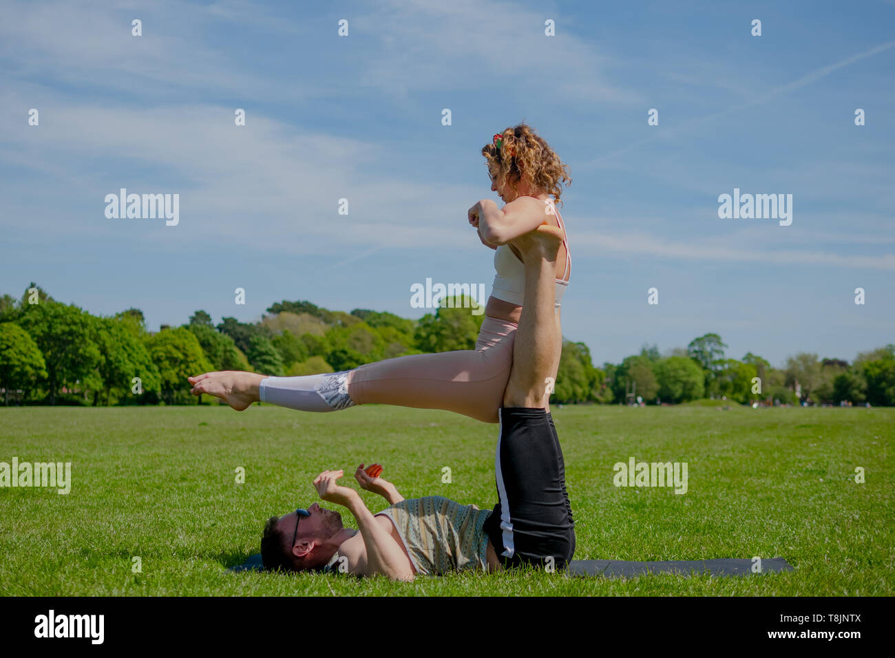 Junge athletische verliebtes Paar Durchführung acro Yoga im Roath Park auf einem hellen, sonnigen Tag. Stockfoto