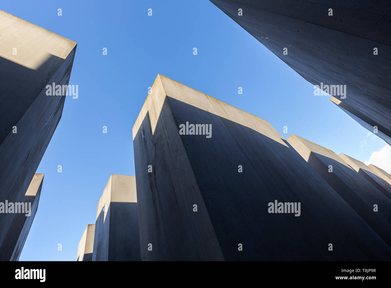 Strahlend blauer Himmel aus zwischen vielen Betonplatten gesehen oder Stelen am Denkmal für die ermordeten Juden Europas (Holocaust-mahnmal), Berlin, Deutschland. Stockfoto