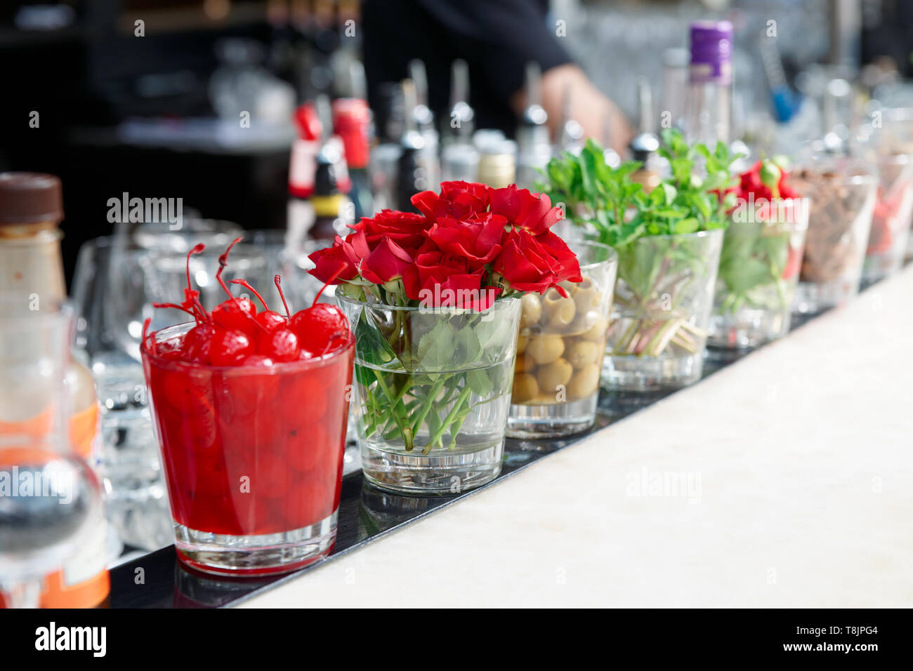 Cocktailkirschen, Kräuter und Blumen auf Theke Stockfoto