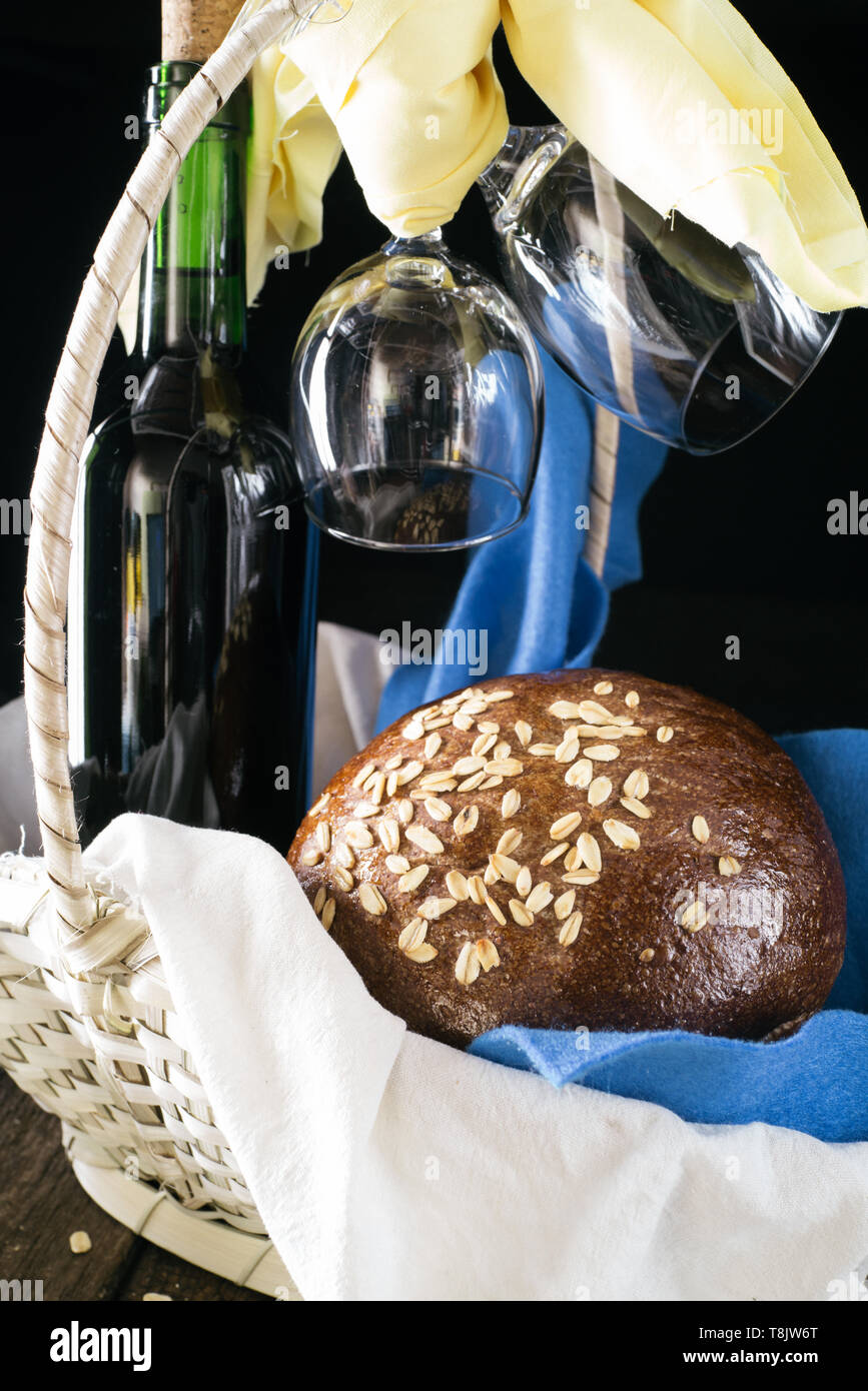 Hausgemachtes Brot in einem Korb mit einer Flasche Wein und zwei Gläser Stockfoto