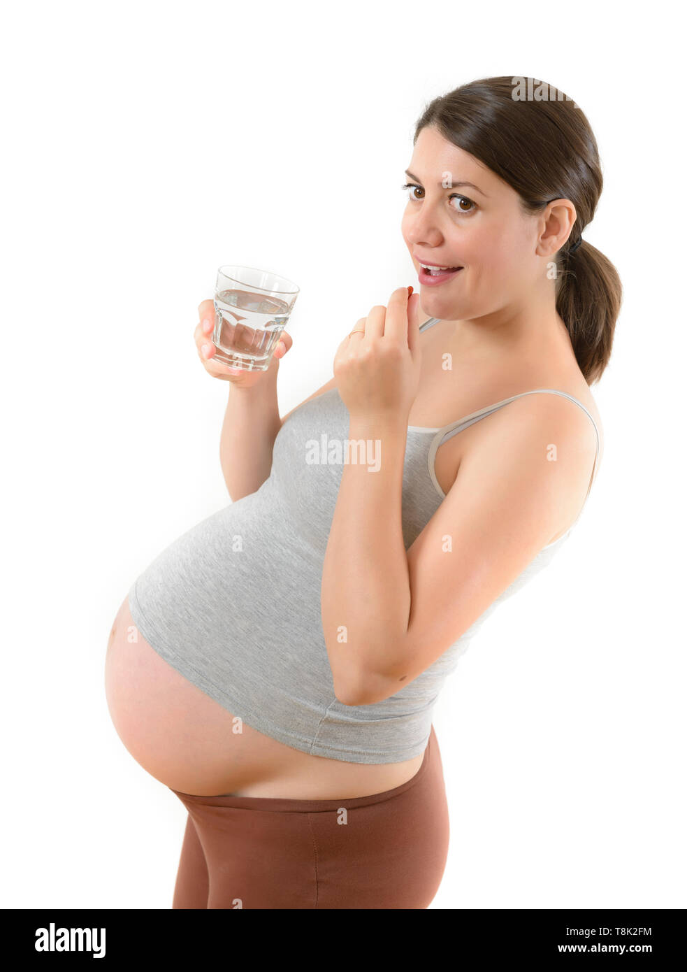 Schönen Lächeln schwangere Frau Einnahme einer Pille auf Weiß isoliert Stockfoto
