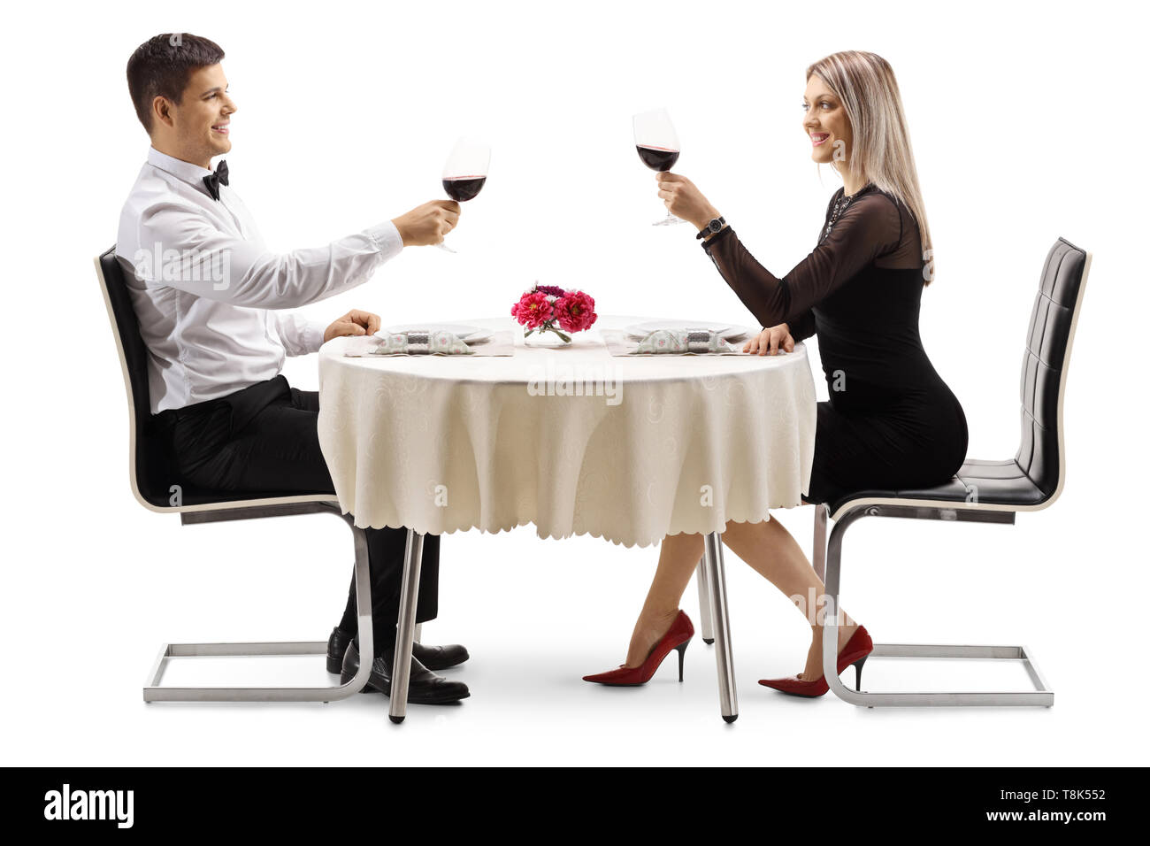 Junge elegantes Paar Toasten mit Wein an einem Tisch auf weißem Hintergrund Stockfoto
