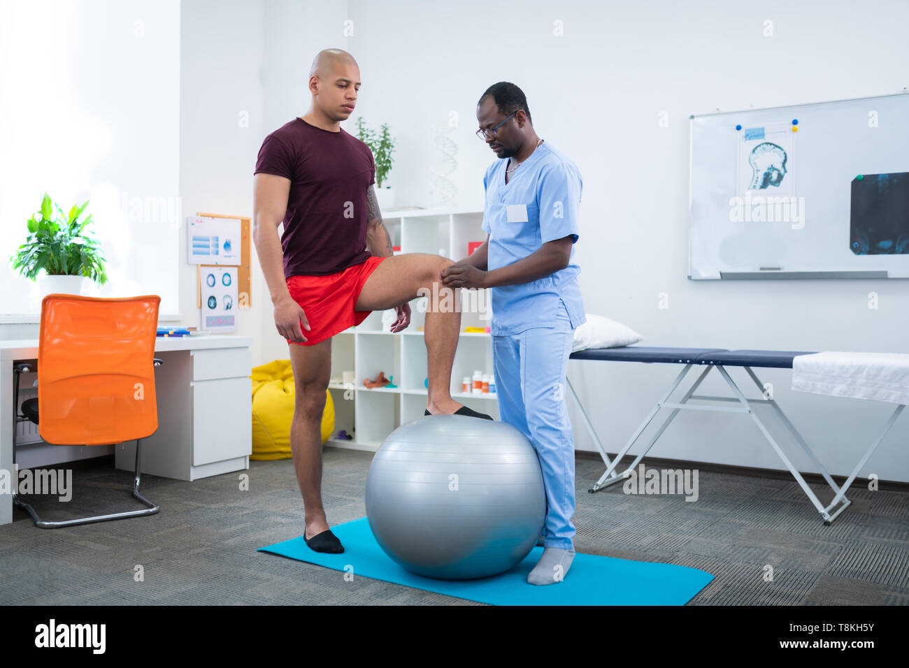 Therapeuten Knie berühren der Sportler in der Nähe von Fit Ball Stockfoto