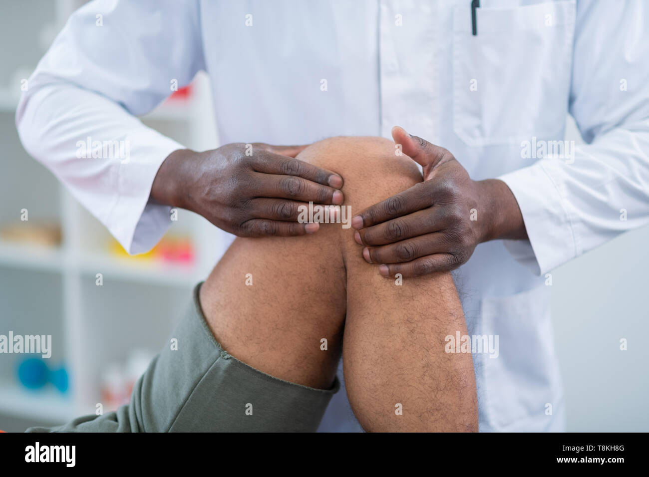 Dunkelhäutige Therapeut die Massage der Knie für Sportler Stockfoto