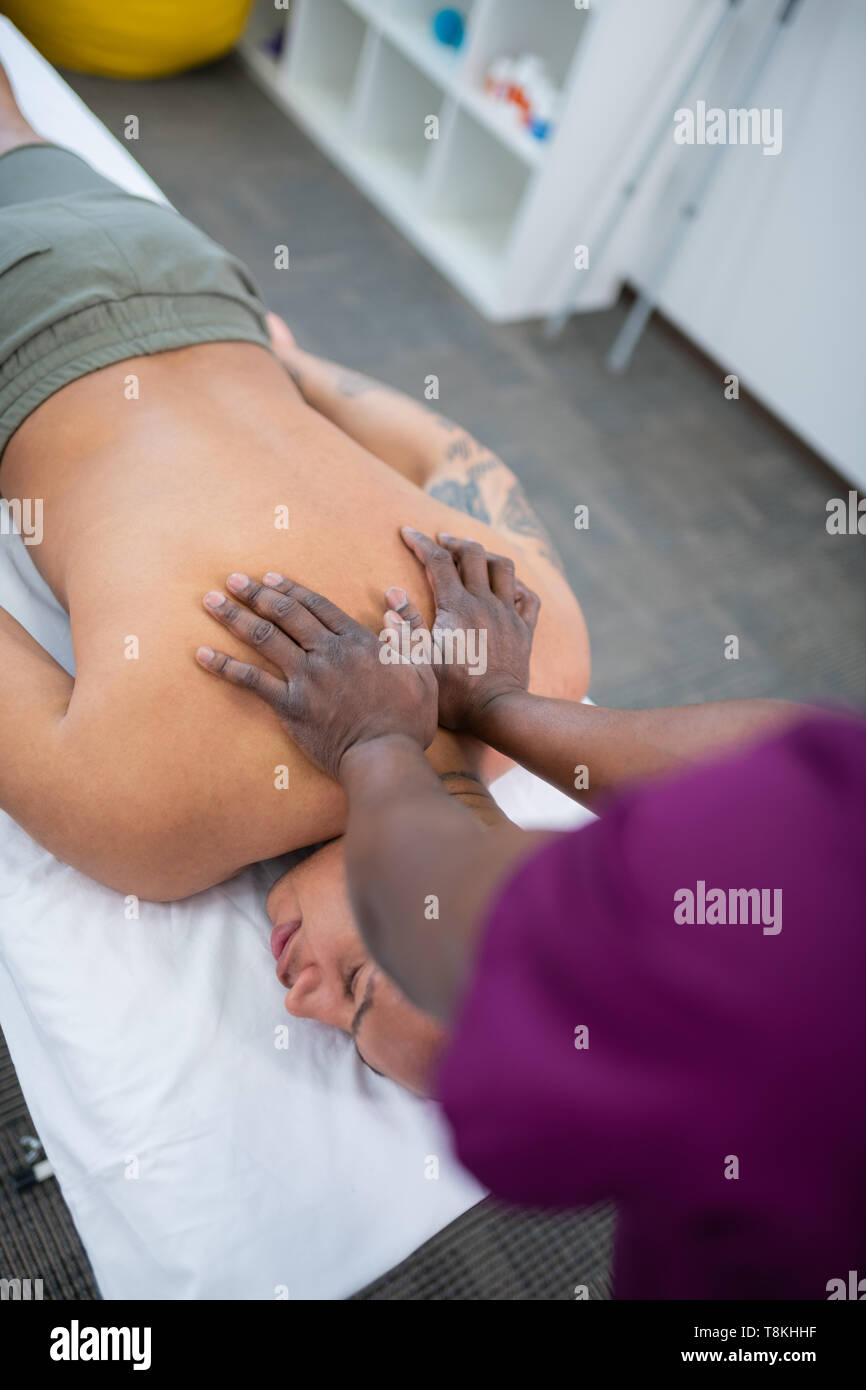 Dunkelhäutige Massage therapist zurück Massieren für glatzköpfige Mann Stockfoto