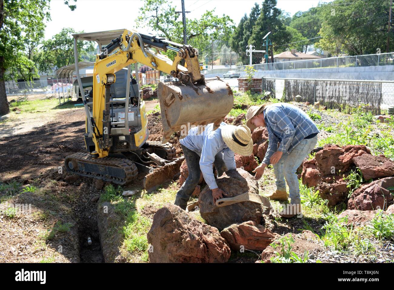 Verschieben von Felsen und der Installation von Rohrleitungen für die Landschaftsgestaltung, die von den mexikanischen Arbeiter mit Bagger und Handwerkzeuge für das Laden und Löschen von Partien in Lake County CA Stockfoto