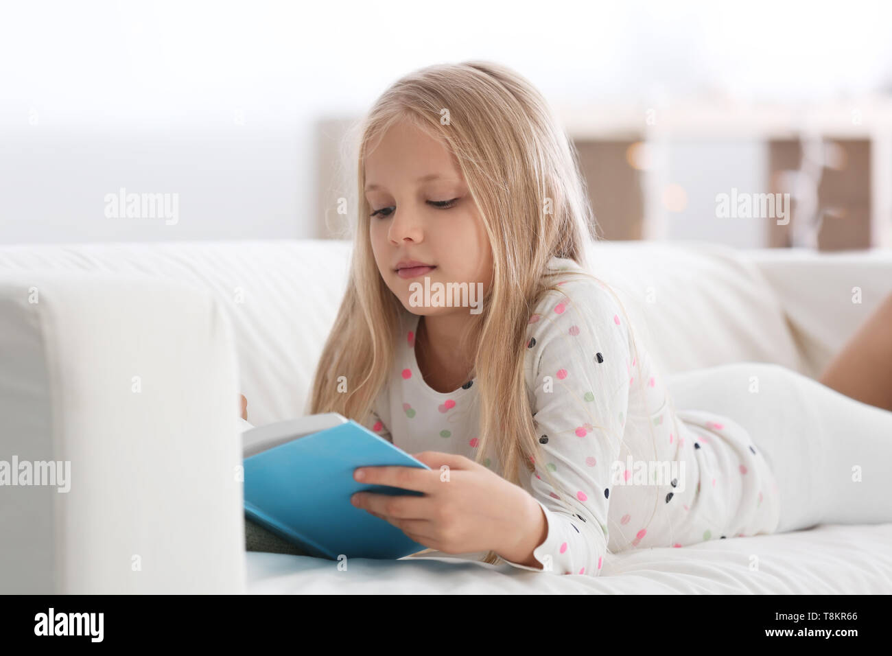 Süße kleine Mädchen lesen Buch auf dem Sofa zu Hause Stockfoto