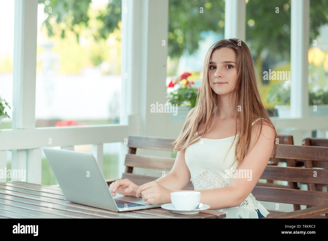 Gerne lässig schöne Frau posiert sie Kamera suchen, vor einem Computer, PC-Laptop  sitzen auf einem Cafe Terrasse. Gemischte Rasse Mädchen, Asiatische C  Stockfotografie - Alamy