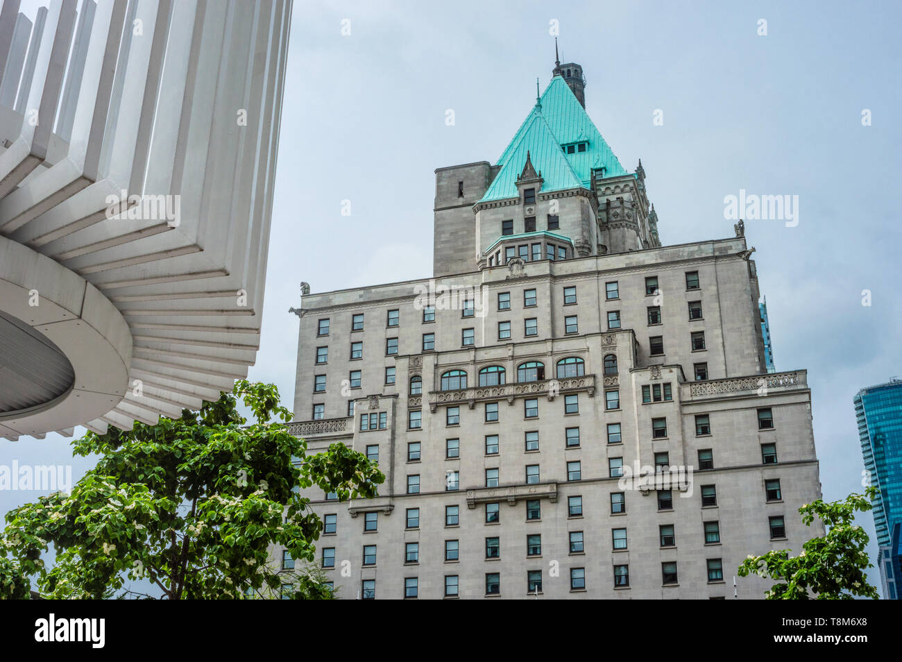 Hotel Vancouver Osten Fassade gegen bewölkten Himmel mit Frühling baum laub im Vordergrund. Stockfoto