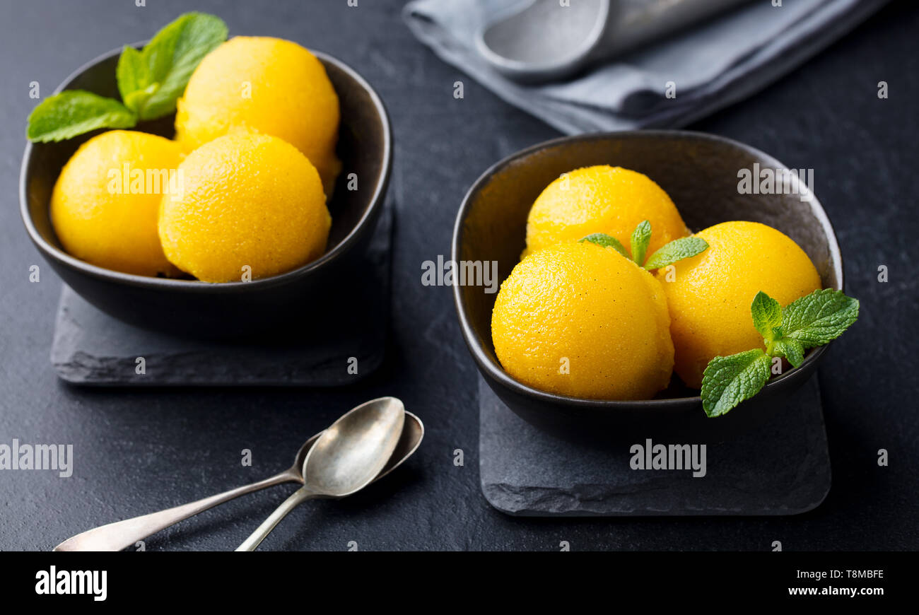 Mango Eis, Tropical Fruit Sorbet in schwarz Schüssel auf schiefer Hintergrund. Stockfoto