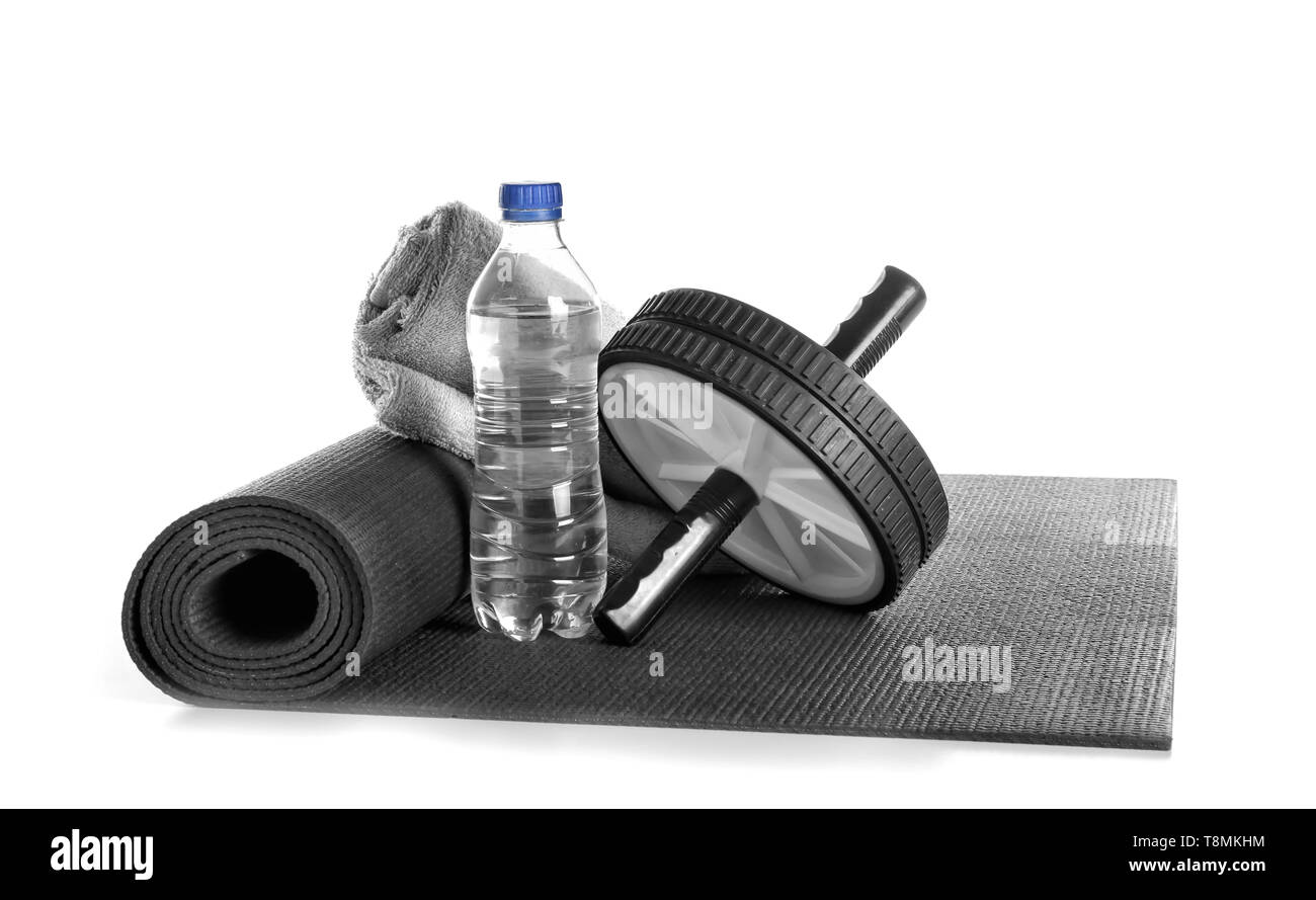 Yoga Matte, Laufrad, ein Handtuch und eine Flasche Wasser auf weißem Hintergrund Stockfoto