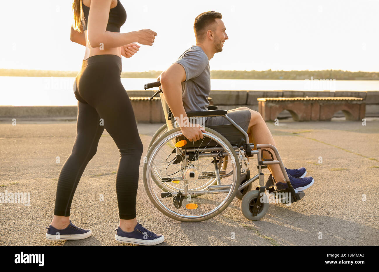 Junger Mann im Rollstuhl und sportliche Frau Training im Freien Stockfoto