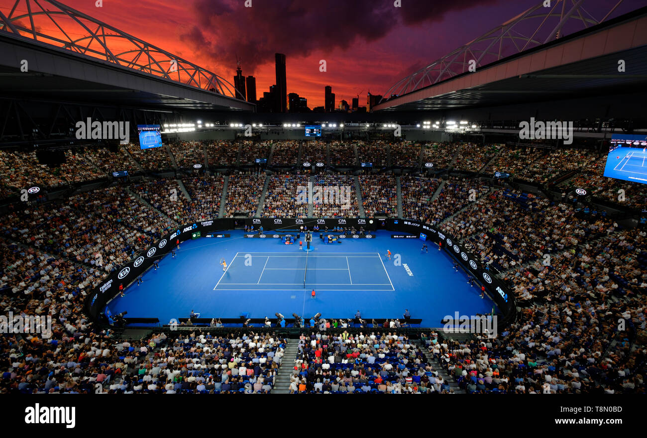 Die Rod Laver Arena bei Sonnenuntergang mit Wahrzeichen von Melbourne Skyline im Hintergrund. Stockfoto