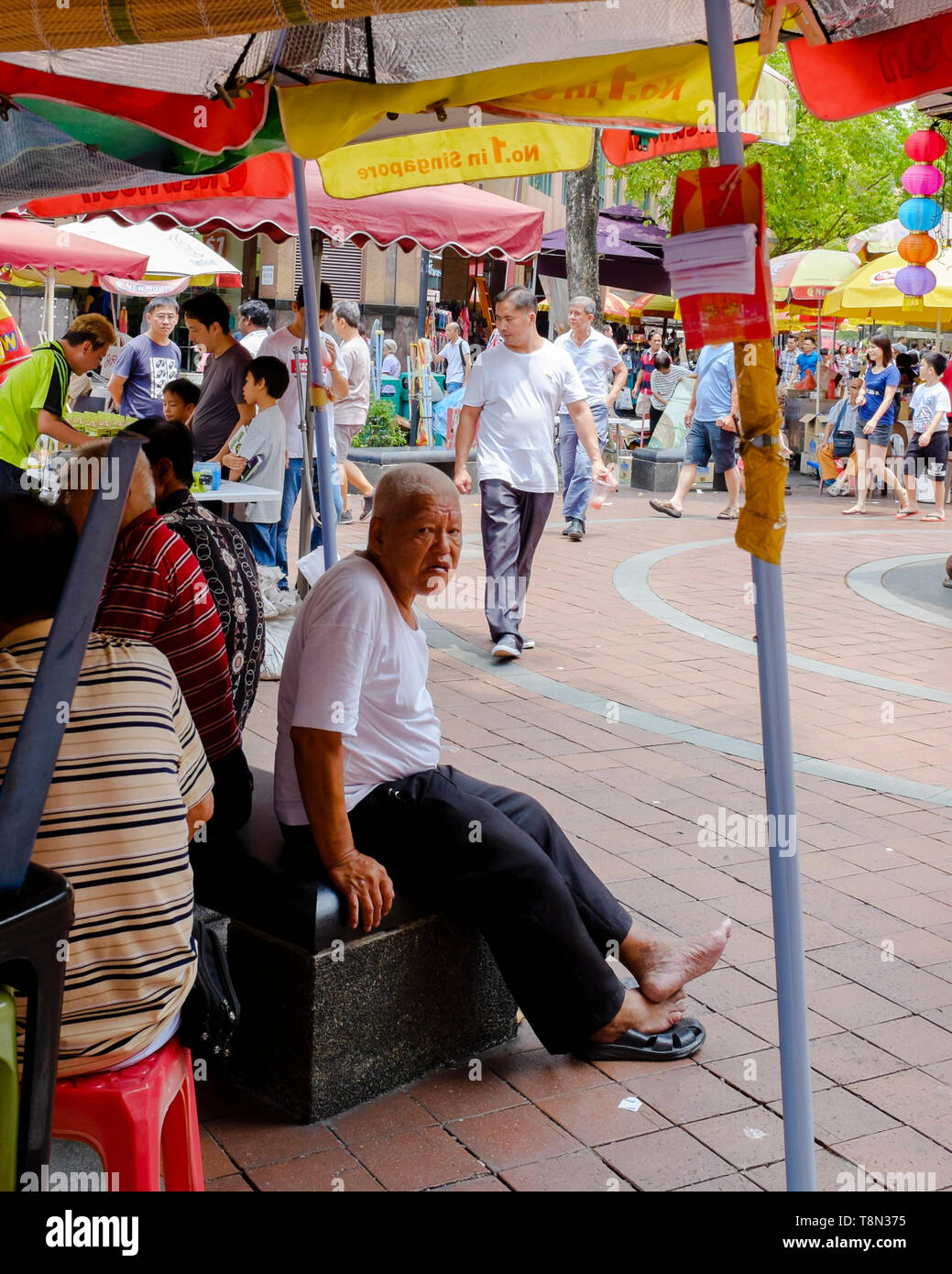 Mann an der Straße sitzen im Marktgebiet in Singapur Abschaltdruck Stockfoto