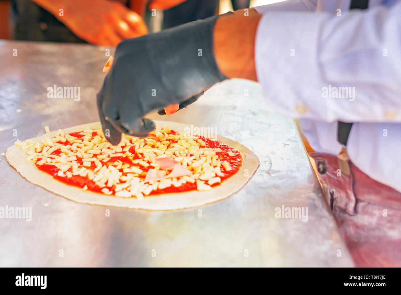 Pizzabäcker vorbereiten, indem Sie eine Pizza Zutaten auf den Teig mit Tomatensoße und Mozzarella. Italienische Küche. Berühmte Rezept. Leckeres Essen Stockfoto