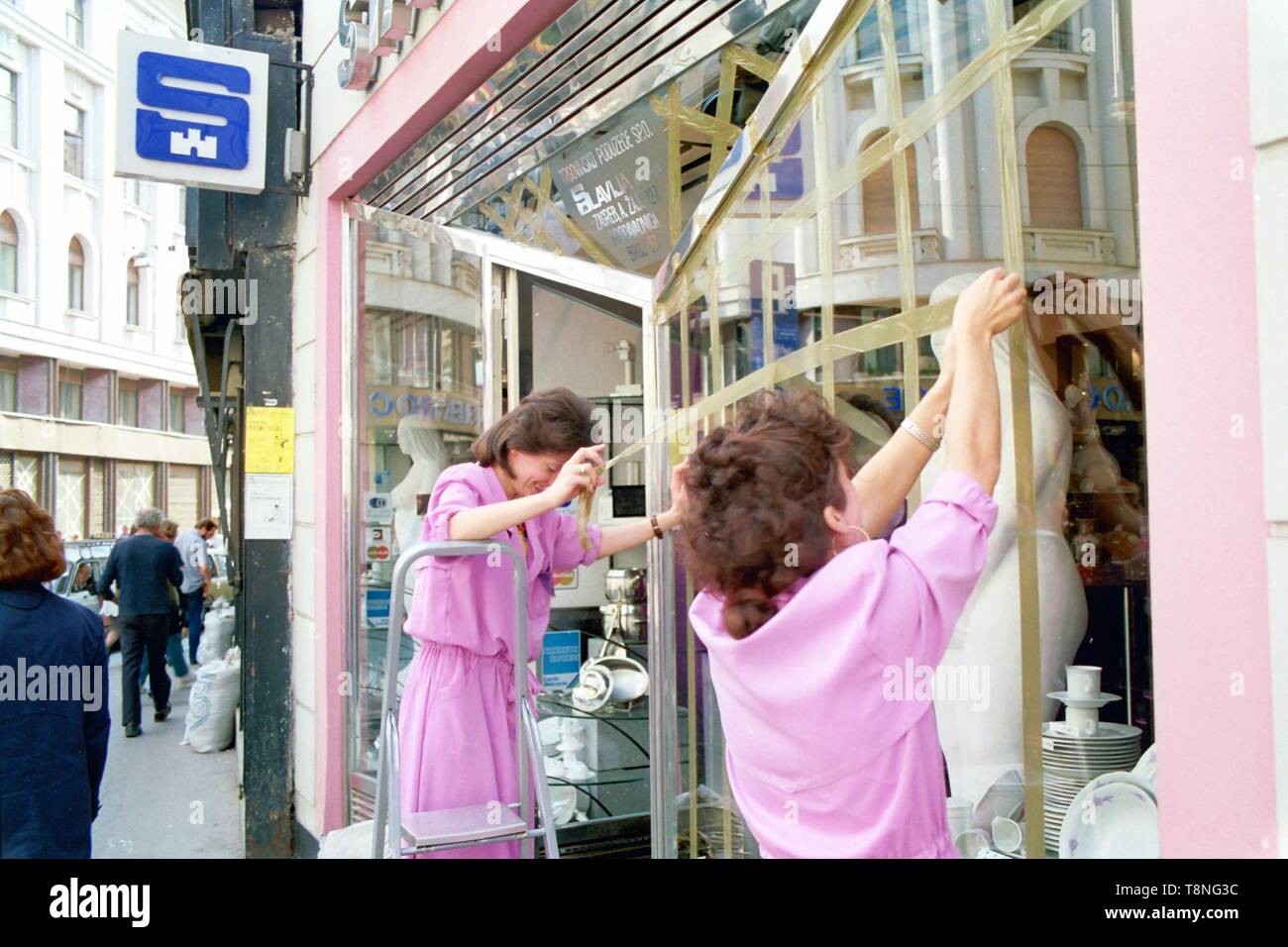 Zwei Frauen, die Band über ein Schaufenster in der kroatischen Hauptstadt Zagreb gegen Bombe Schäden durch Luftangriffe während des serbisch-kroatischen Krieg zu Guard in 1991-92. Bild von Adam Alexander Stockfoto