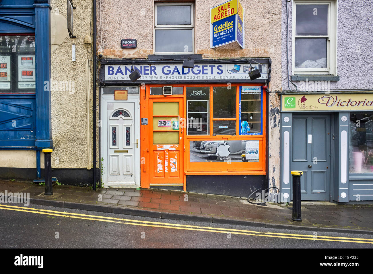 Ein geschlossen Telefon entsperren Shop mit einer ungeeigneten UPVC-Kunststoff Tür angrenzenden Stockfoto